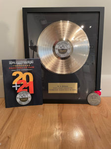 To the left is a 2021 plaque, and to the right is a silver-plated record with a plaque beneath it.